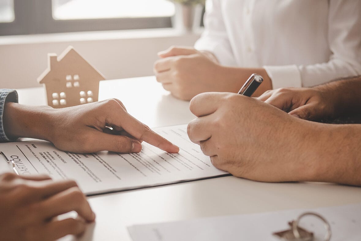 Close-up of homeowners reviewing and signing a home sale agreement, representing the first step toward a hassle-free and profitable Max Out Homes transaction.